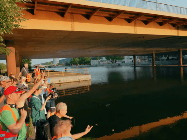 ilnehmende des Neckar Tribunals stehen unter einer Brücke am Neckar und zeigen auf den Fluss. Die Veranstaltung setzt sich für die Rechte und den Schutz des Neckars als Ökosystem ein.