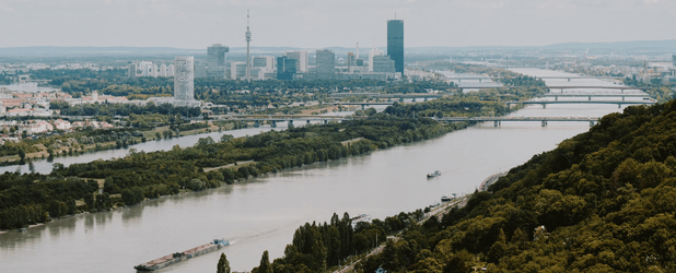 Luftaufnahme von Wien mit Donau, Brücken und grünen Landschaften, Symbolbild zum Artikel über eine Wirtschaft für das Leben.