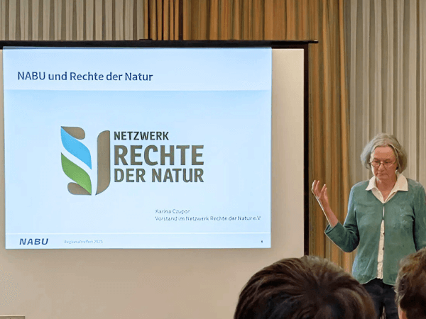 Karina Czupor hält für den NABU einen Vortrag des Netzwerks Rechte der Natur, NABU- und Rechte-der-Natur-Logos im Hintergrund sichtbar. Foto: Leo Schäfer