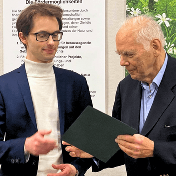 Stifter Georg Winter übergibt Dr. Felix Aiwanger den Preis für seinen Aufsatz „Verträge mit der Natur“.